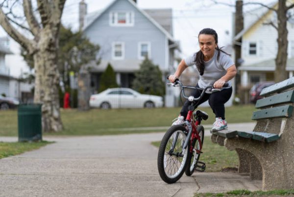 confident young woman with dwarfism rides a bike on residential neighborhood path
